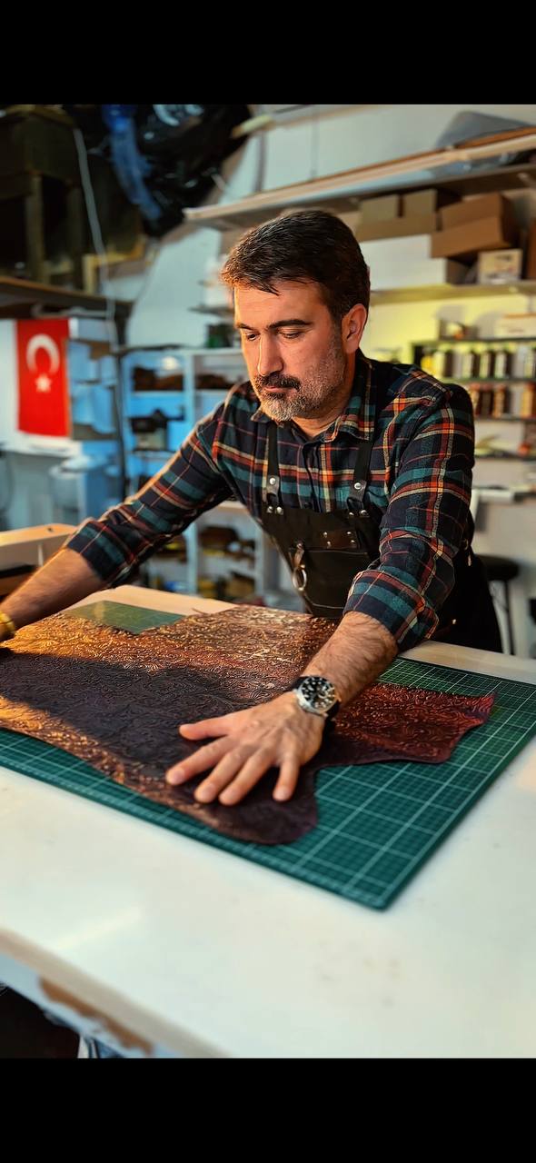 Hands working an embossed leather hide in the partner workshop in Türkiye